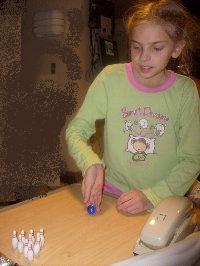 Playing a little bowling table-top game she got as gift